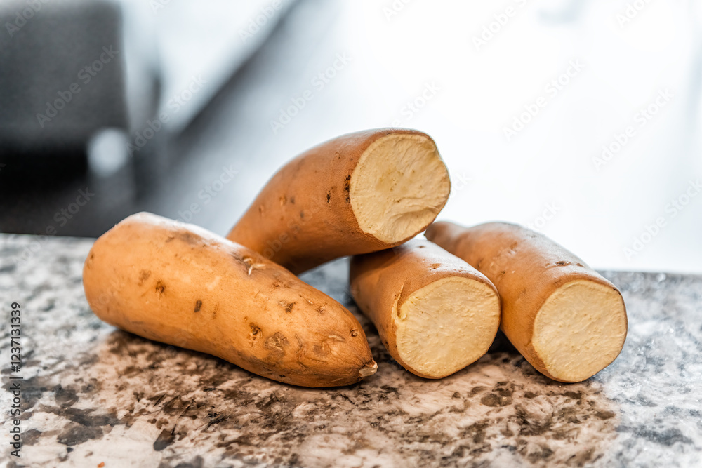 Table with closeup of raw vegetables uncooked tan colored Hannah sweet whole potatoes with cross-section Table with closeup of raw vegetables uncooked tan colored Hannah sweet whole potatoes with cross-section