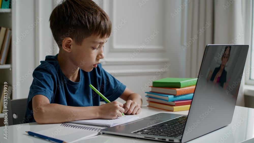 Young student writing intently in notebook during virtual classroom, engaging with digital learning environment from home laptop workspace. Teaching child at home Young student writing intently in notebook during virtual classroom, engaging with digital learning environment from home laptop workspace. Teaching child at home