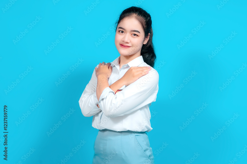 Young female student dressed in a uniform Standing With Hand on Heart Against Bright Blue Background Young female student dressed in a uniform Standing With Hand on Heart Against Bright Blue Background