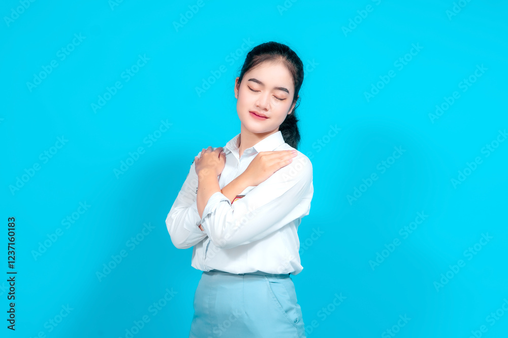 Young female student dressed in a uniform Standing With Hand on Heart Against Bright Blue Background Young female student dressed in a uniform Standing With Hand on Heart Against Bright Blue Background
