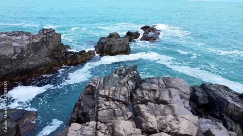 Aerial view Top down seashore. Waves crashing on rock cliff.