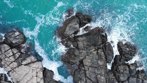 Aerial view Top down seashore. Waves crashing on rock cliff.