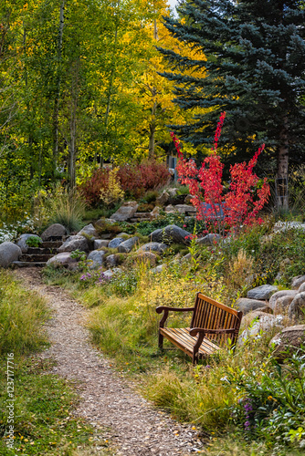 Beaver Creek, Colorado ski resort in autumn fall and bench by aspen trees in park vertical view with red tree