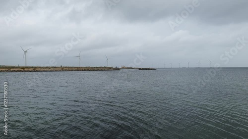 Seascape view with large wind turbines in the distance. Baltic Sea. Buildings are visible in the distance.