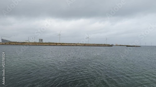 Seascape view with large wind turbines in the distance. Baltic Sea. Buildings are visible in the distance.