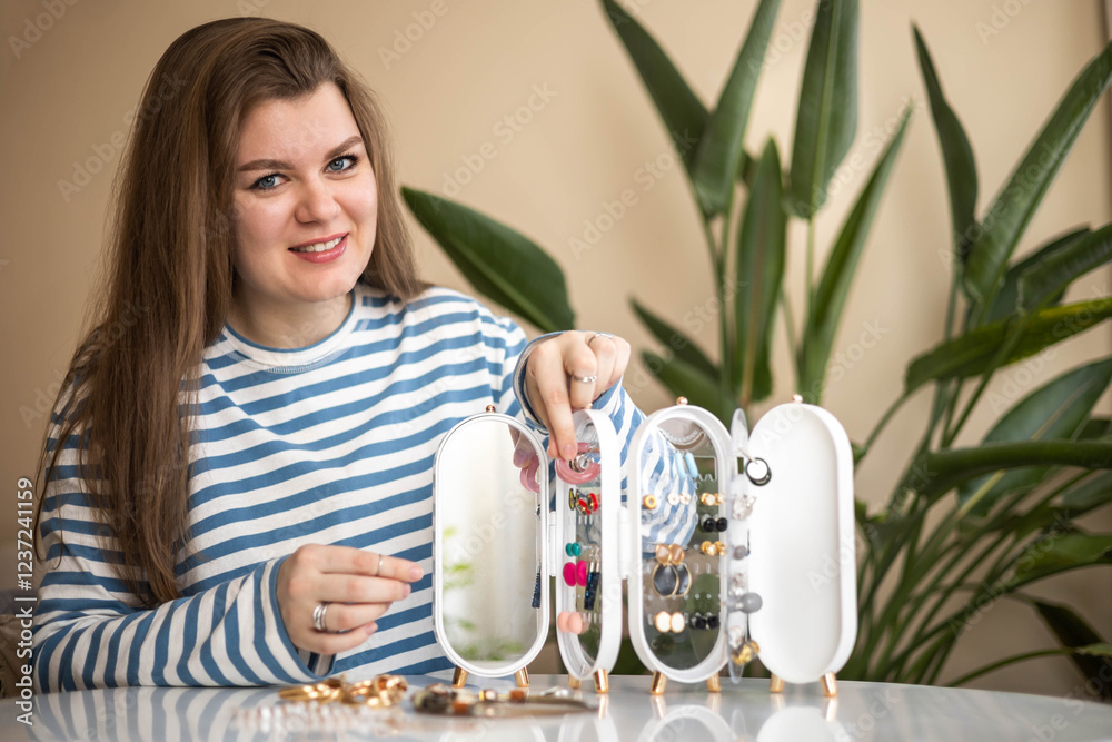 A young woman chooses earrings for herself. Storage of jewelry and costume jewelry. A young woman chooses earrings for herself. Storage of jewelry and costume jewelry.