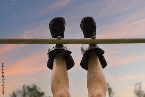 Close-up of men's legs in gravity boots on a horizontal bar. View from below, focus on the legs, exercise for the back. photo