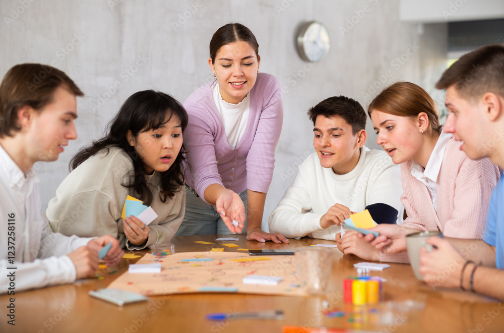 Group of happy young people playing board game Group of happy young people playing board game