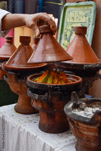 Hand lifting a tagine while cooking with delicious typical Marrakesh food inside