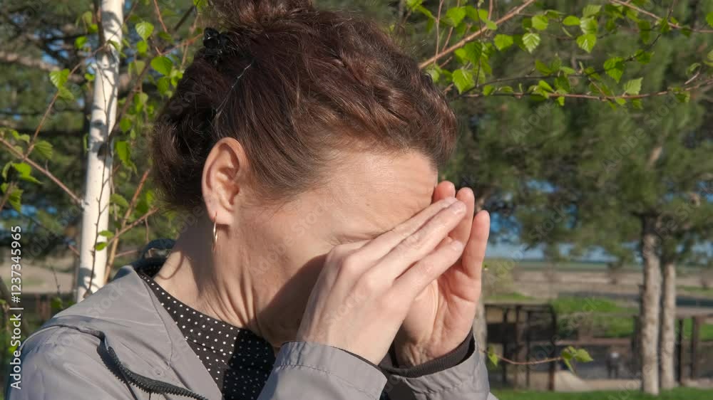 Lady scratching nose by spring tree. A view of unhappy woman scratching her nose in the green garden during day time. Lady scratching nose by spring tree. A view of unhappy woman scratching her nose in the green garden during day time.