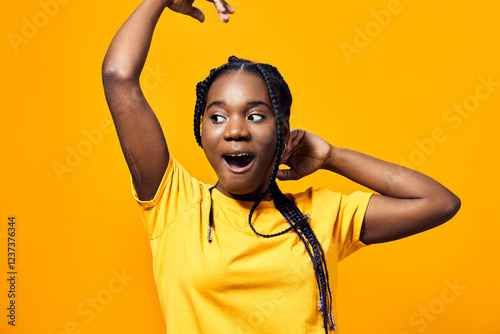 Joyful Black girl expressing excitement in a vibrant yellow t shirt against a bright yellow background, showcasing energetic emotions and playful vibes photo