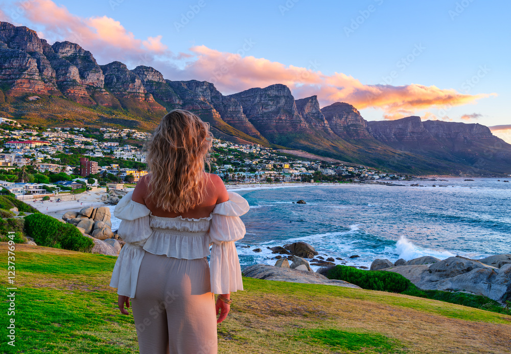 A young white girl admiring the breathtaking view of the Twelve Apostles, Camps Bay, and the Atlantic Ocean from Maiden's Cove in Cape Town, South Africa