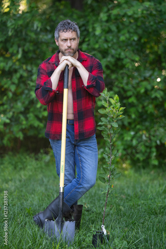 A gardener near plants ant tree in a garden. A man pruning a tree in an orchard. A gardener planting fruit tree in a garden. A gardener tending to tree in a farmyard. A farm with rows of fruit trees. photo