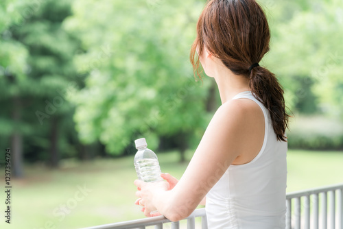 公園・森林の中でミネラルウォーターを飲む若いアジア人女性
 photo