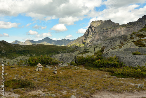 Ritual stone pyramids in a clearing in the lowland of a mountain valley at the foot of a mountain with a human profile.