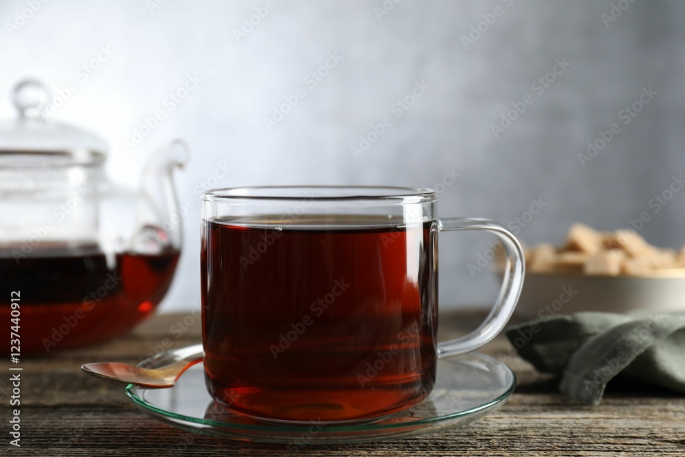Aromatic black tea in cup and spoon on wooden table, closeup Aromatic black tea in cup and spoon on wooden table, closeup
