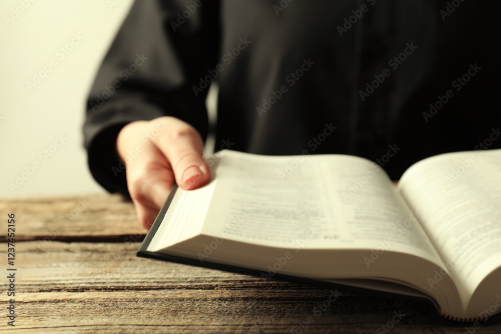 Woman with Holy Bible in English language at wooden table, closeup Woman with Holy Bible in English language at wooden table, closeup