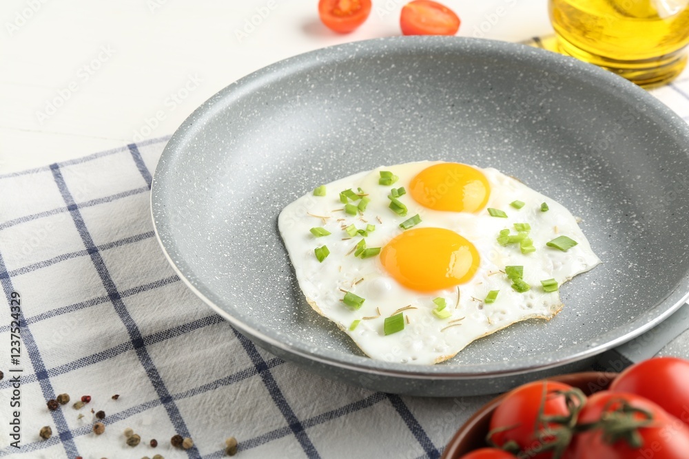 Tasty fried eggs with green onion in frying pan on table, closeup Tasty fried eggs with green onion in frying pan on table, closeup