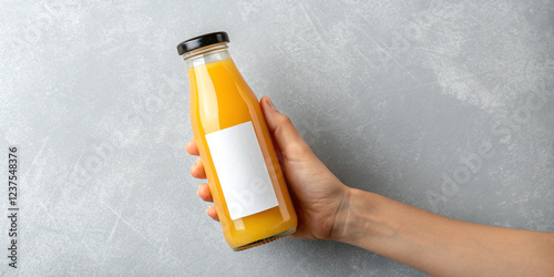 A Hand Holding a Bottle of Orange Juice with a Blank Label, Indicating Refreshment and Potential