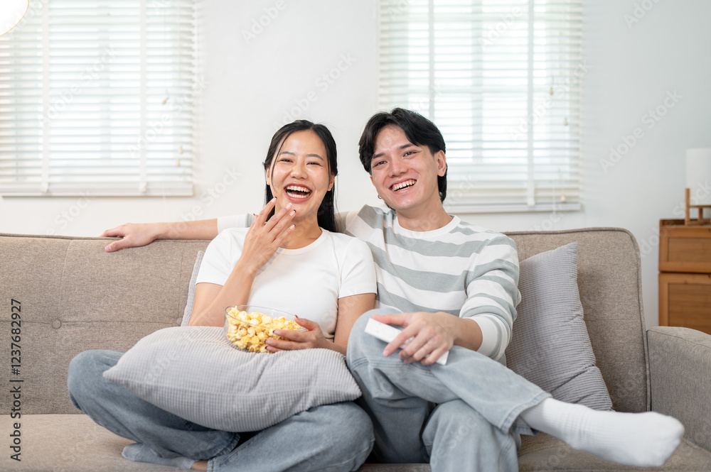 Cheerful Asian boyfriend and girlfriend enjoy watching a movie on the TV, having a fun time at home. Cheerful Asian boyfriend and girlfriend enjoy watching a movie on the TV, having a fun time at home.