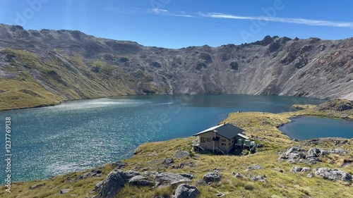 Remote alpine lake near Angelus Hut, New Zealand, surrounded by rugged mountains and open skies, establishing overview photo