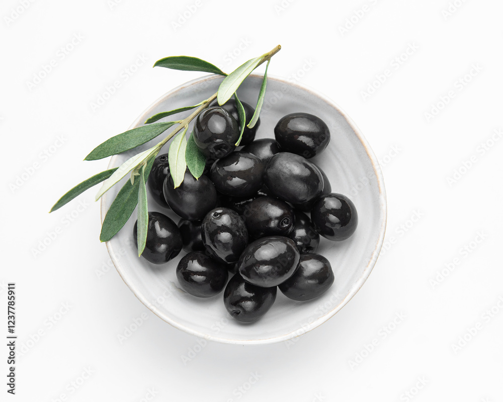 Black olives with leaves in a bowl on white background Black olives with leaves in a bowl on white background