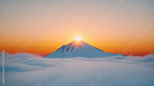 Majestic sunrise over snow-capped mountain peak surrounded by soft clouds at dawn