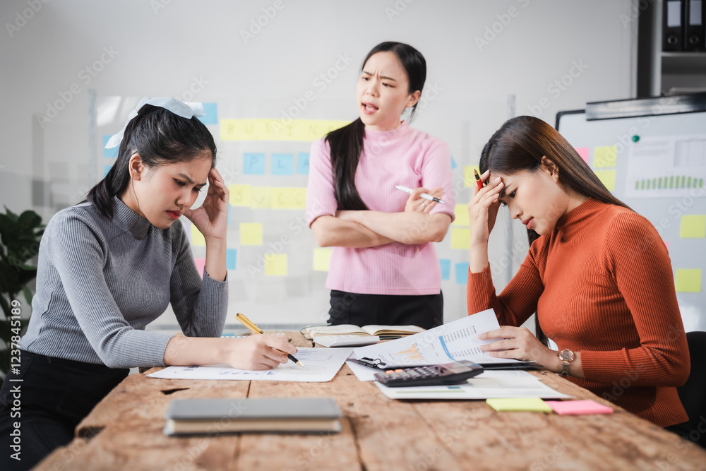 Fototapeta premium Asian people, frustrated businesswoman sits at desk, grappling with challenges of her startup, acknowledging failure, and seeking ways to learn and grow. team meeting. blamed
