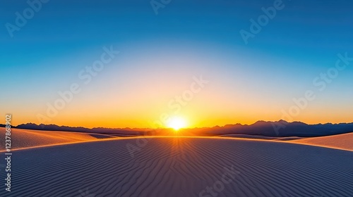 Sunrise over a vast desert landscape with rippling sand dunes and distant mountains
