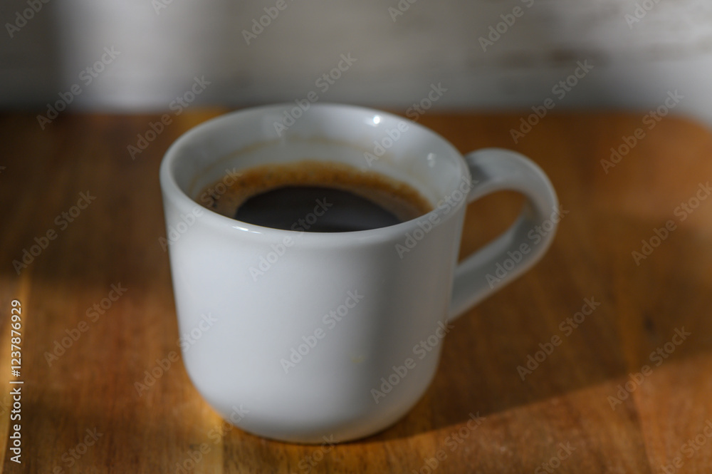Cozy morning ritual of sipping a rich cup of coffee in soft natural light on a wooden table Cozy morning ritual of sipping a rich cup of coffee in soft natural light on a wooden table