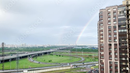 The landscape of the city with high-rise buildings, a traffic interchange and a rainbow in the sky