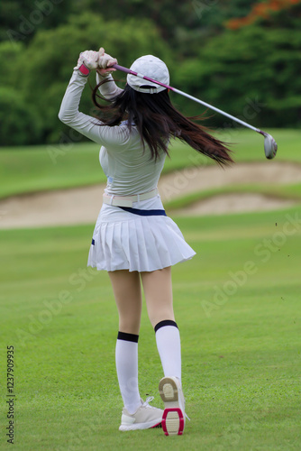 Wallpaper Mural  Asian woman happy and fun while playing golf on the golf course. Golfer hitting golf shot with driver club on course. Beautiful woman smiling and holding a golf club while standing on green lawn. Torontodigital.ca