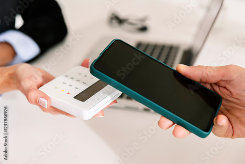 Hand of woman paying through smart phone on credit card reader photo