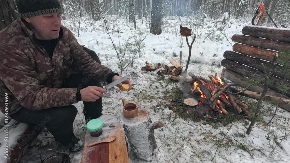 A man drinks tea in a winter forest cooked on a fire A man drinks tea in a winter forest cooked on a fire