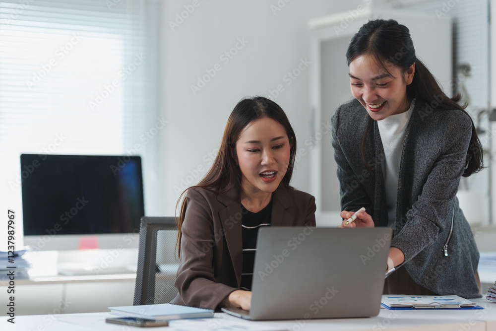 Two asian businesswomen are collaborating on a project, using a laptop in a modern office environment, discussing strategies and analyzing data Two asian businesswomen are collaborating on a project, using a laptop in a modern office environment, discussing strategies and analyzing data