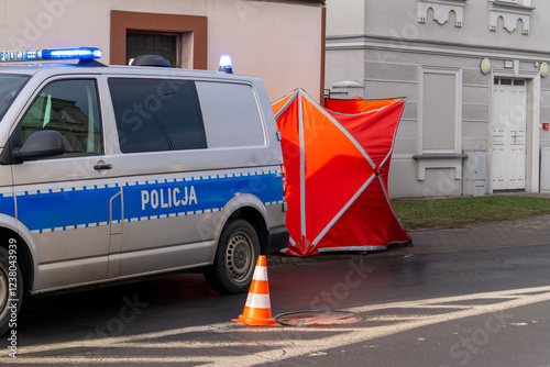 the scene of a fatal road accident in the city. bodies covered with a red fire brigade screen. A police car stands on the road with blue traffic lights. securing the accident site. photo