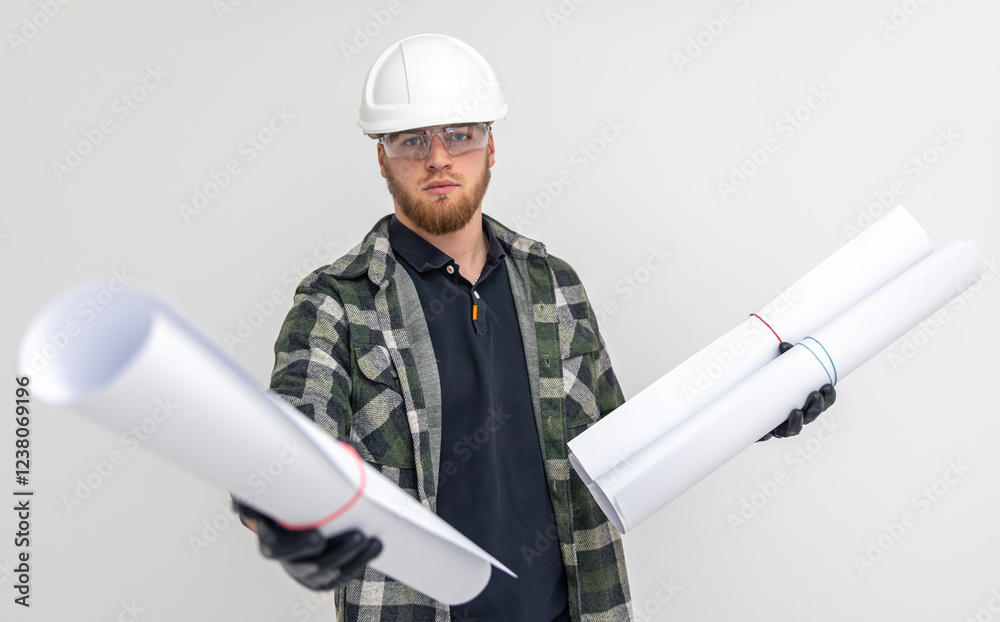 Fototapeta premium Male builder. Engineer in overalls and helmet holds blueprints and projects in his hands.
