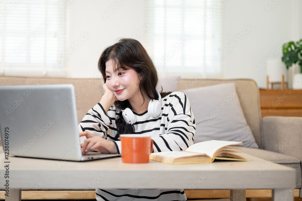 A beautiful Asian female student sits at a coffee table, researching information on the internet. A beautiful Asian female student sits at a coffee table, researching information on the internet.