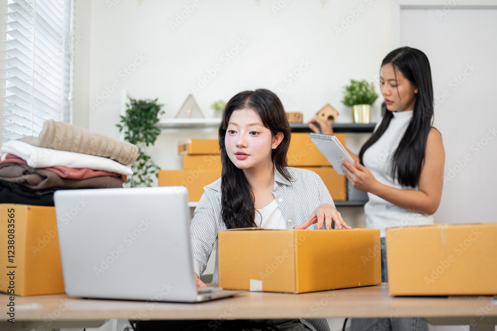 A beautiful Asian female is packing client orders while her colleague is reviewing stock items. A beautiful Asian female is packing client orders while her colleague is reviewing stock items.
