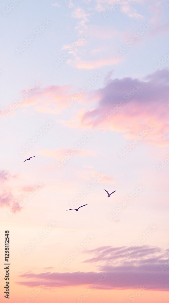 Fototapeta premium Graceful Birds in Flight Against a Dreamy Pink and Purple Sunset Sky, Minimalist Nature Photography Phone Wallpaper in 4K Ultra HD