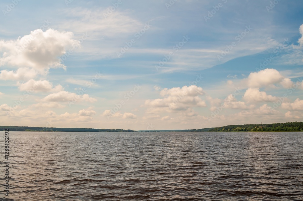 Obraz premium A picturesque summer lake scene unfolds under a partly cloudy sky, offering a tranquil and serene view.