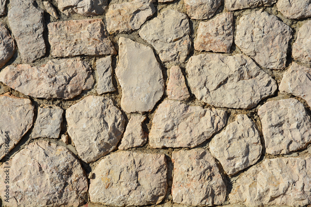 Detail of a wall made of natural, irregularly shaped stones, creating a rustic and textured surface Detail of a wall made of natural, irregularly shaped stones, creating a rustic and textured surface