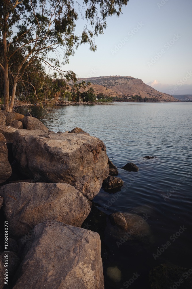 Tranquil lake with a rocky shoreline and distant hills under a clear sky, perfect for nature lovers. Tranquil lake with a rocky shoreline and distant hills under a clear sky, perfect for nature lovers.