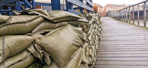 Stacked sand bags to protect homes by a city water stream against flooding photo