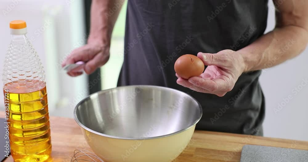 Professional chef cracks eggshell with sharp knife. Experienced cook prepares ingredients for cooking delicious pancakes in kitchen. Slow motion