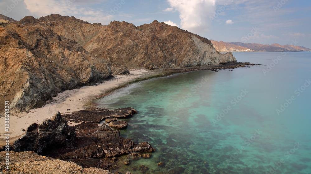The Western part of Qantab Beach, located 15 km East from Muscat, Oman, with desert landscape, clear water and rocky mountains. Qantab is a traditional fishing village