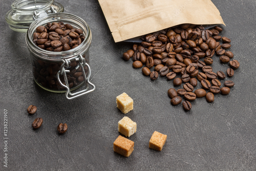 Roasted coffee beans in glass jar and in paper bag.