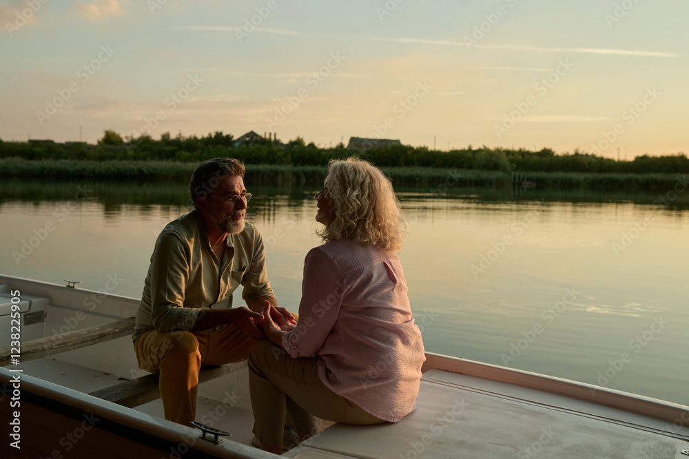 Fototapeta premium Senior couple holding hands and enjoying a romantic sunset boat ride