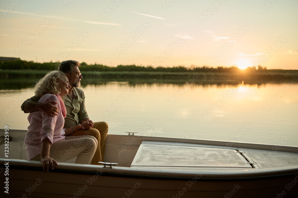 Fototapeta premium Romantic senior couple enjoying sunset boat ride on lake