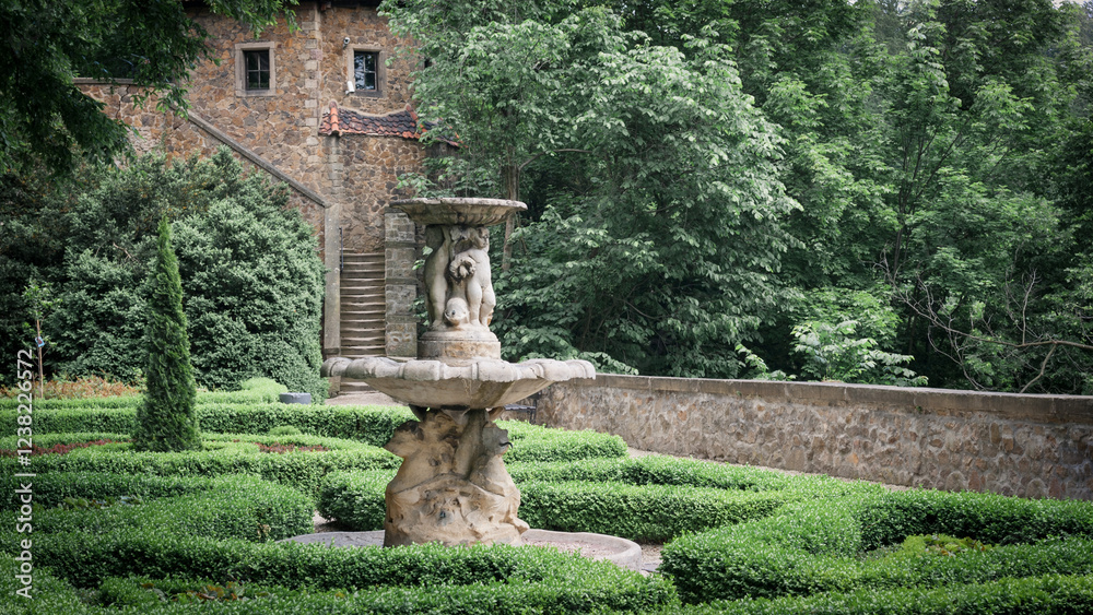 Formal Garden with a Fountain and a Stone Building.